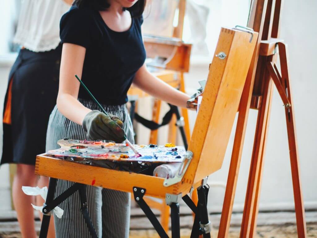 Artist mixing oil painting on wooden palette