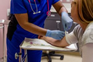 Medical Assistant putting a tourniquet around a patients arm before she draws blood