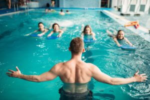 Trainer works with female group in swimming pool