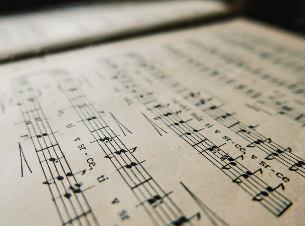 Close-up image of An old book with music notes. Sheet music with notes and lyrics.