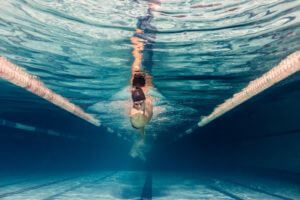 underwater picture of young swimmer in cap and goggles training in swimming pool